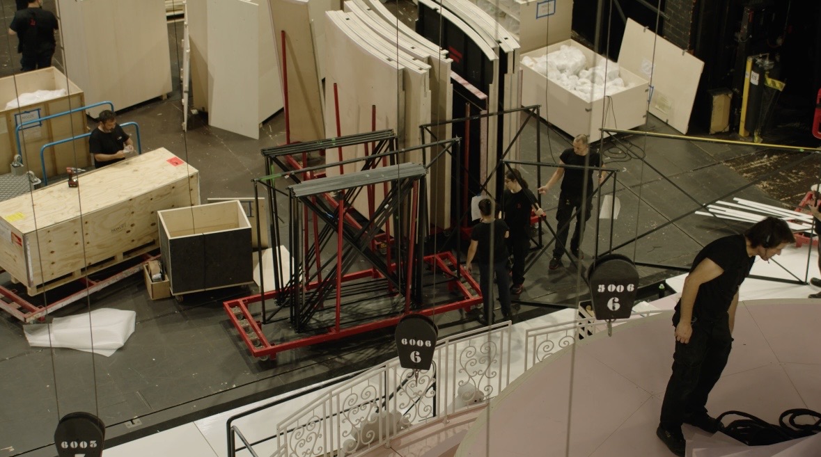Backstage crew moving set pieces on a theatre stage