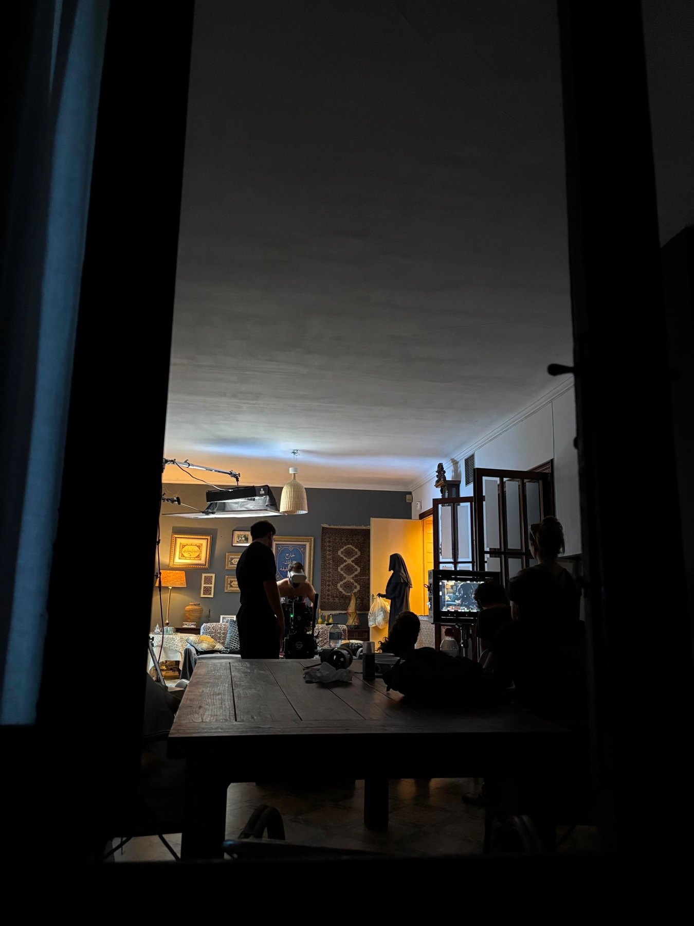 Crew in silhouette in a dark room, the lit set beyond