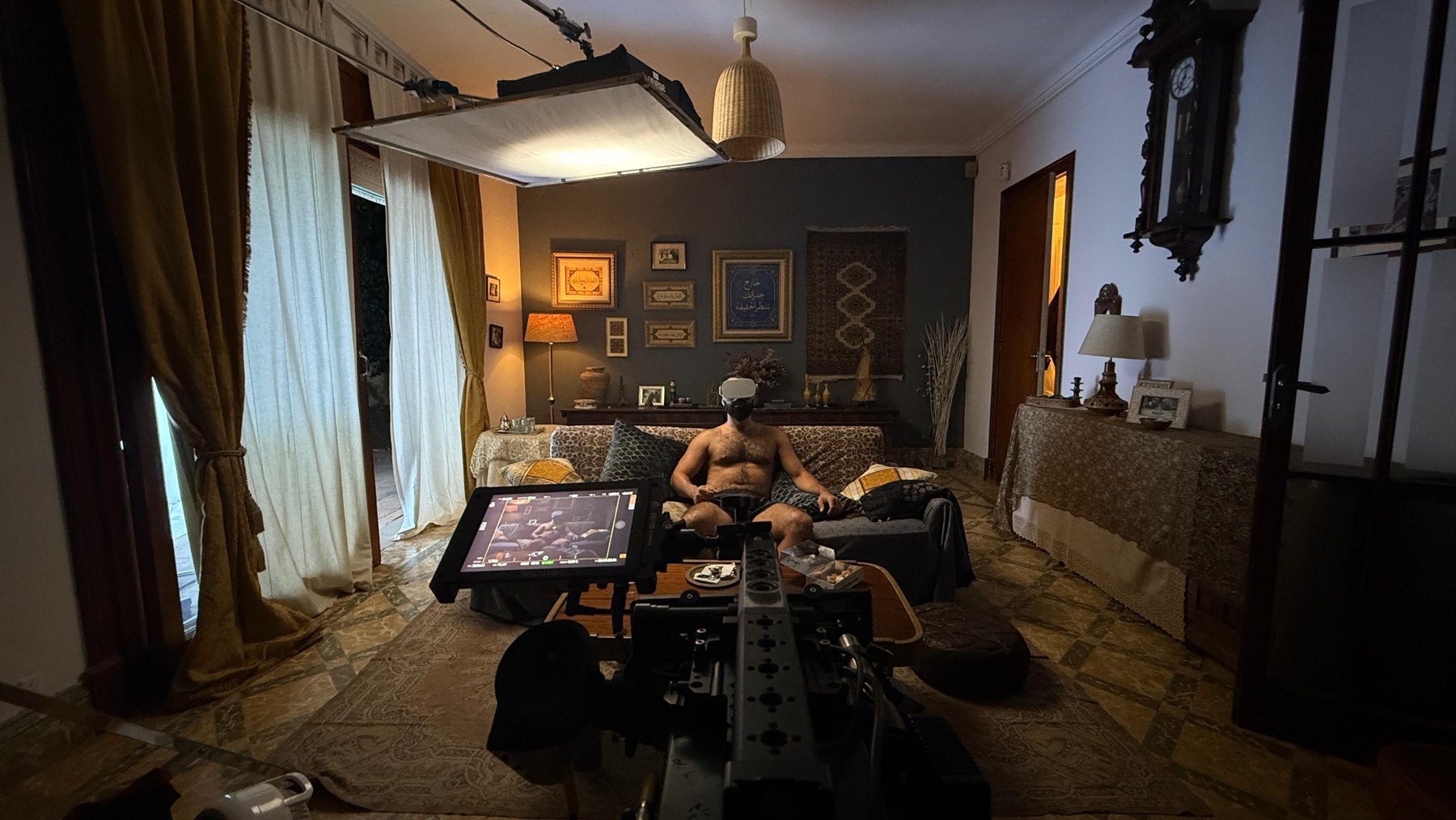 Living room set: camera and monitor facing a man with a VR headset on the sofa