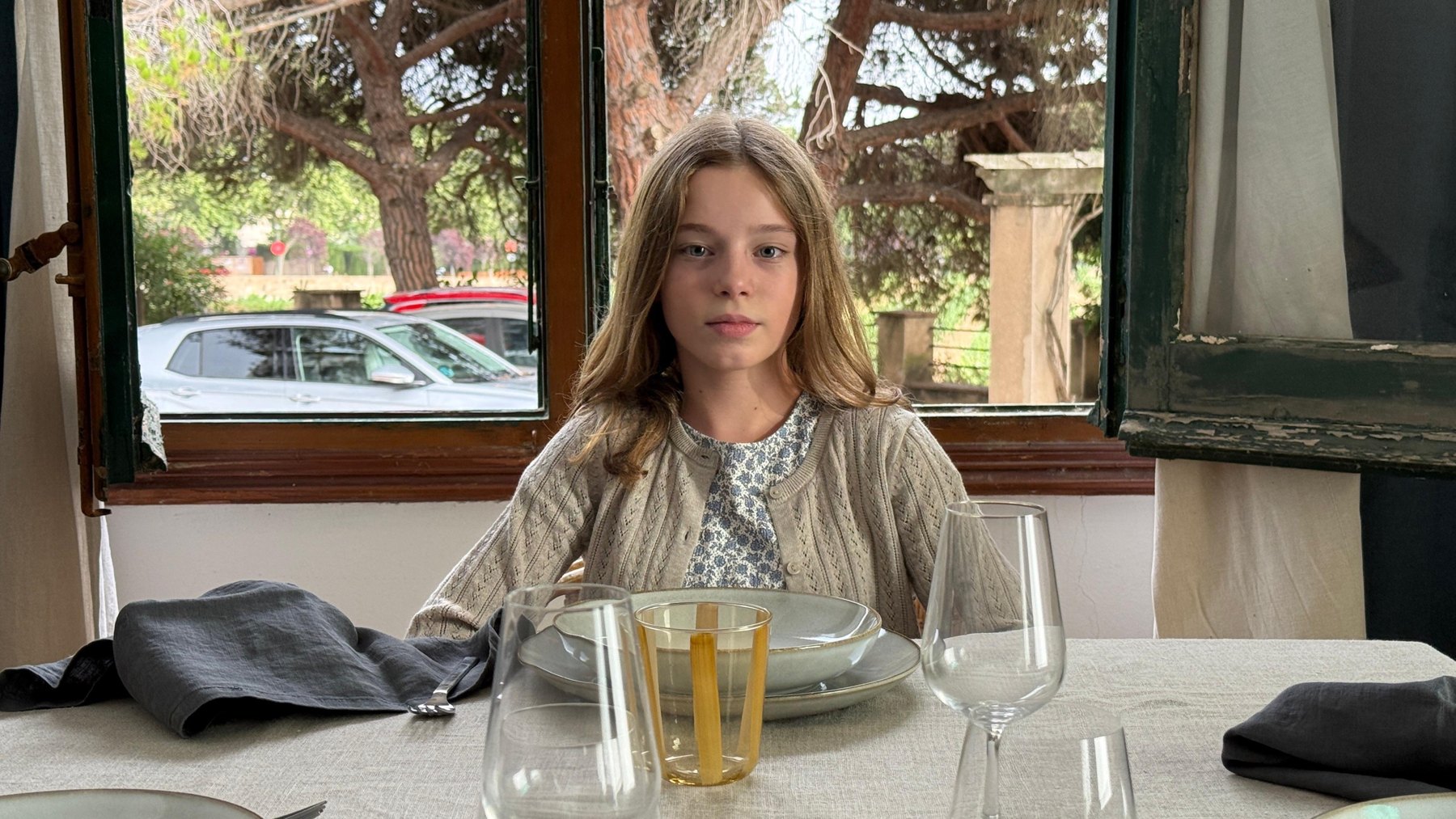 Girl sitting at a set dinner table by the window