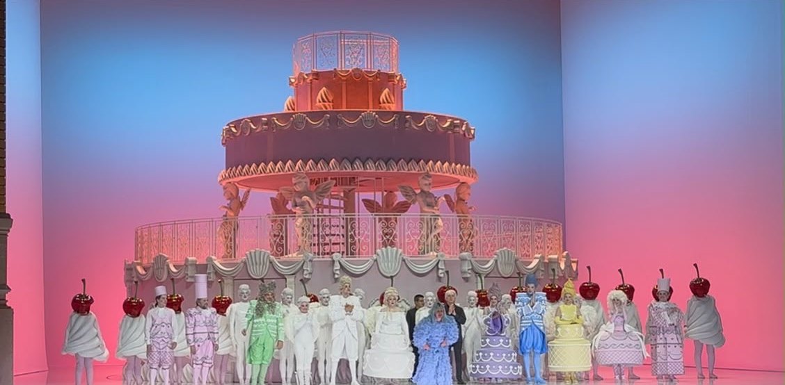Curtain call in front of the giant cake, performers dressed as cherries and cakes