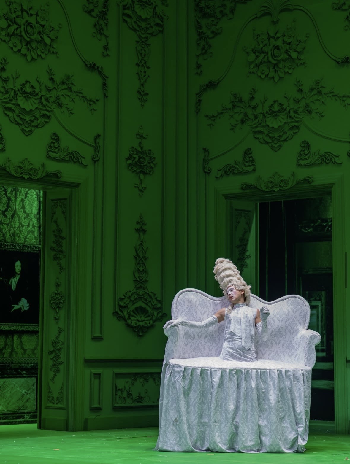 Performer in white baroque costume on a green stage